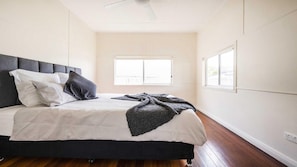 A bedroom with a bed, pillows, a blanket, a window, and a ceiling fan.