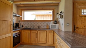A kitchen with wooden cabinets, a built-in oven, a microwave, and a window above the sink. - Quiet 2-bedroom apartment with terrace in Samoëns (Samoëns)