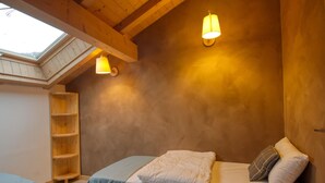 A cozy bedroom with a sloped ceiling, a skylight, and two wall-mounted lamps. - Quiet 2-bedroom apartment with terrace in Samoëns (Samoëns)