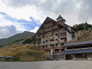 A multi-story hotel with balconies, a ski lift, and a mountainous backdrop.