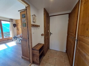 A wooden interior with a bench, a door, and a view of a balcony.
