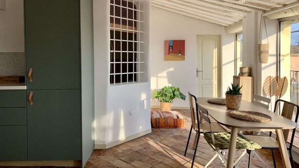 A kitchen with a green cabinet, a window with a grid, and a dining area with a table and chairs. - Magnificent apartment with terrace and rooftop view (Aix-en-Provence)