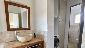 A bathroom with a wooden vanity, a sink, a mirror, a washing machine, and a toilet. - Magnificent apartment with terrace and rooftop view (Aix-en-Provence)