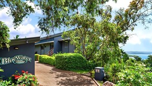 A BlueWater Views hotel with a view of the ocean, a paved pathway, and lush greenery.