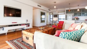 A spacious living room with a large flat-screen TV, a wooden coffee table, and a comfortable sofa. - Luxury Condo & Spectacular View by FeelHome (Tel Aviv)