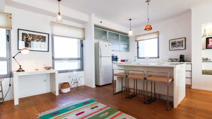 A modern kitchen with a central island, bar stools, and pendant lighting. - Luxury Condo & Spectacular View by FeelHome (Tel Aviv)