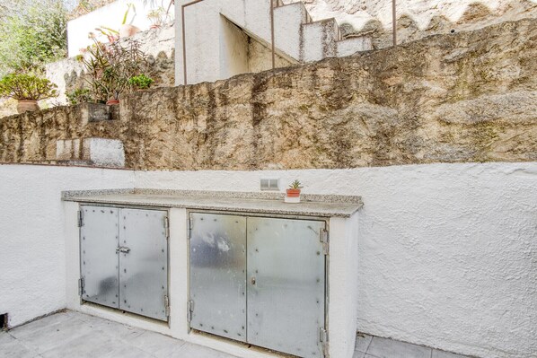 Un mur blanc à la surface rugueuse et texturée, et un meuble métallique à deux portes.