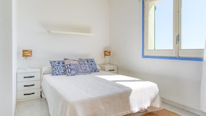 A bedroom with a bed, two bedside tables, a window, and a wall-mounted shelf. - MALLORCA 15 Canyelles Roses (Rosas / Roses)