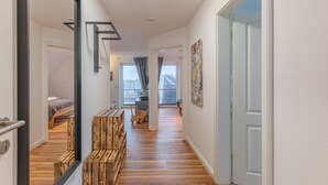 Ein modernes Interieur mit Holzboden, einer Treppe mit Geländer und Blick ins Freie durch große Fenster.