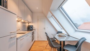 Eine moderne Küche mit weißen Schränken, einer Arbeitsplatte aus Granit und einem Oberlicht über einem Esstisch mit zwei Stühlen.