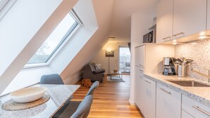 Eine moderne Küche mit Oberlicht, Holzboden und einem Essbereich mit Tisch und Stühlen.