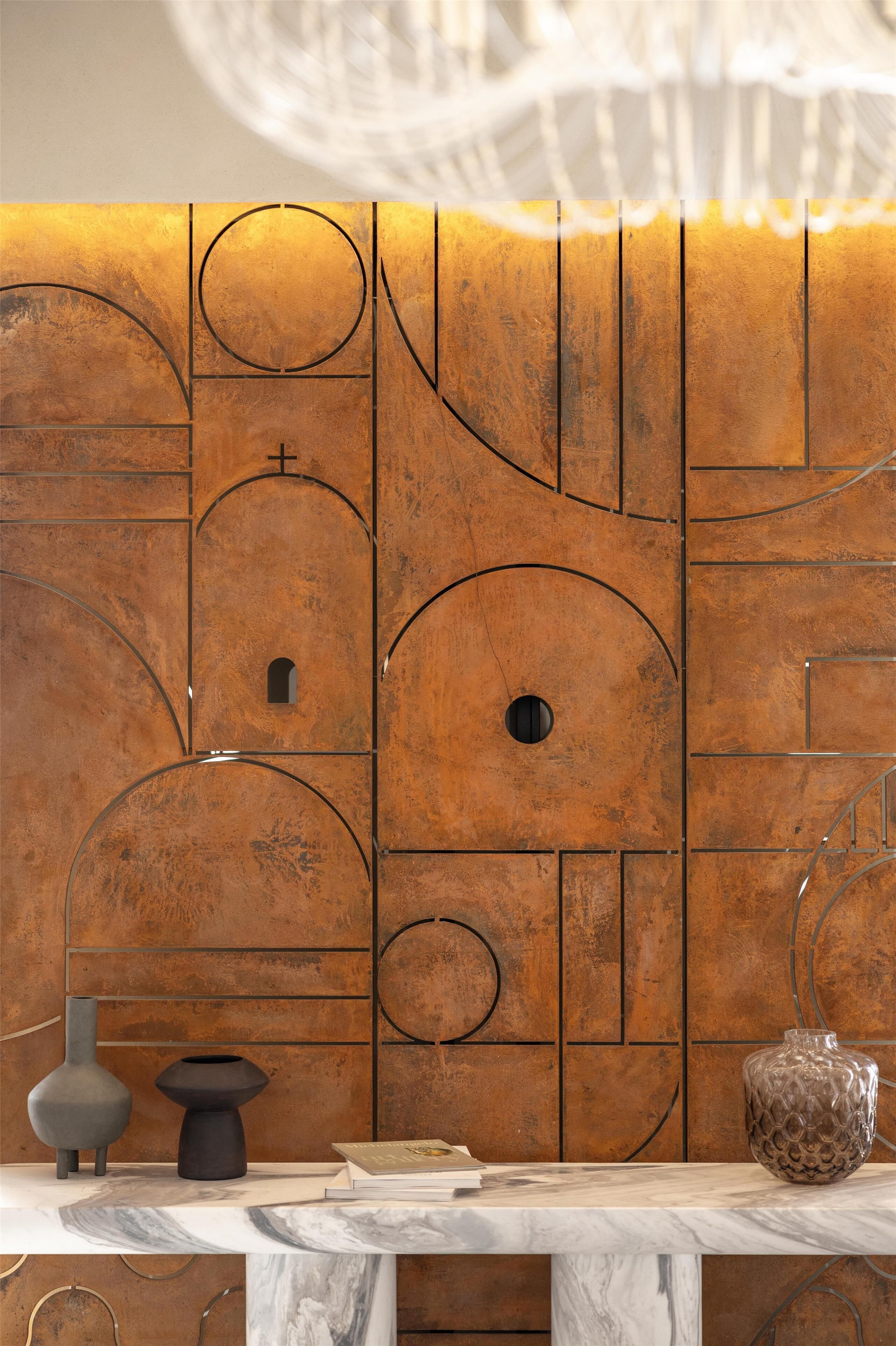 A modern interior with a marble table, geometric wall design, and decorative vases.