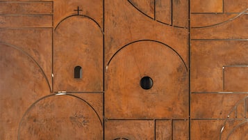 Un intérieur moderne avec une table en marbre, un motif géométrique sur le mur et des vases décoratifs.