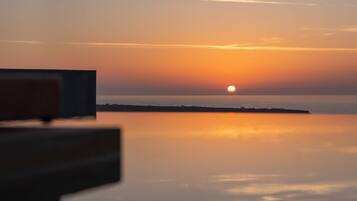 A sunset over a calm sea with a distant shoreline.