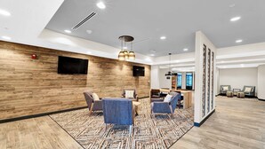 A modern lobby with a wooden wall, a patterned rug, and seating areas. - Candlewood Suites Detroit - Auburn Hills by IHG (Auburn Hills)