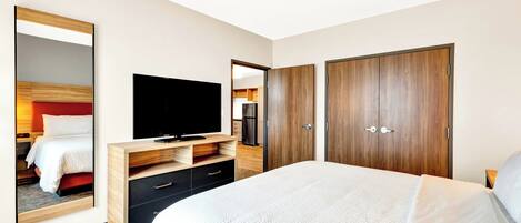 Ett hotellrum med en stor säng, en TV, en garderob och en spegel.