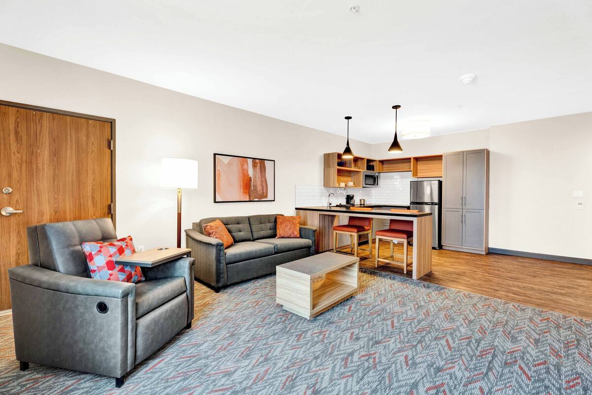 A modern living room with a grey sofa, a wooden coffee table, and a patterned rug.