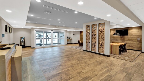 A spacious lobby with a wooden floor, a reception desk, a seating area, and a wall-mounted TV. - Candlewood Suites Detroit - Auburn Hills by IHG (Auburn Hills)