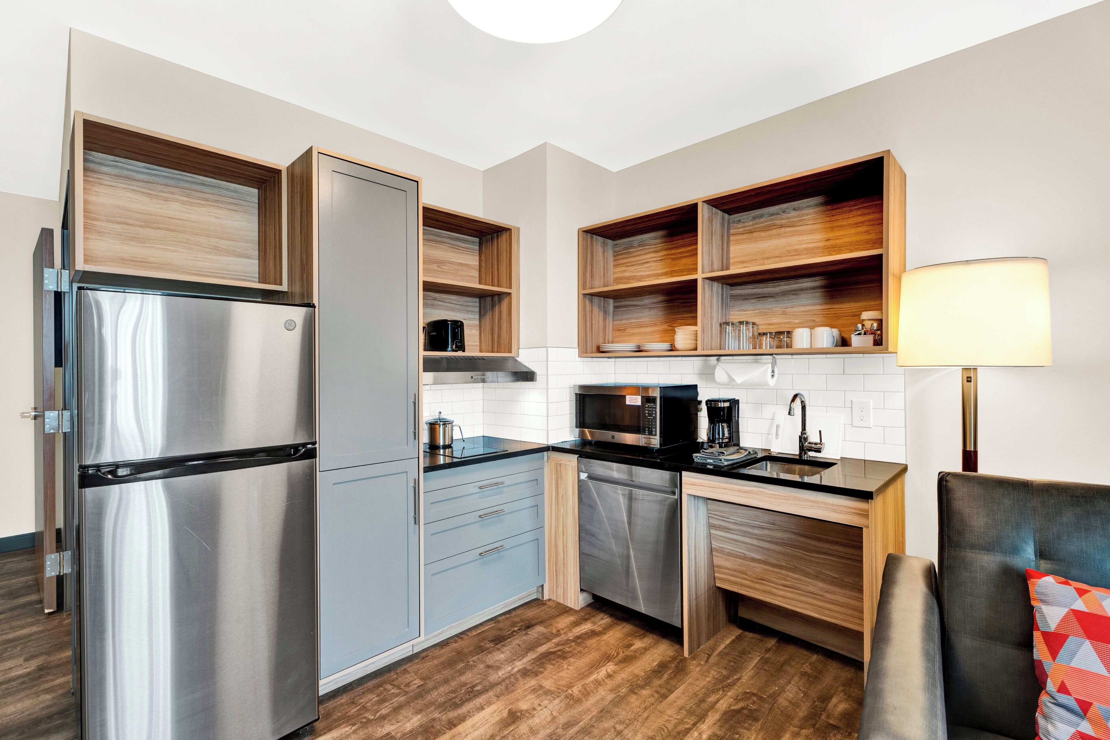 A modern kitchen with a stainless steel refrigerator, wooden cabinets, and a built-in microwave.