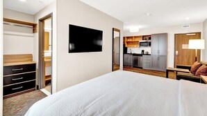 A hotel room with a large bed, a TV, a wardrobe, and a kitchenette in the background. - Candlewood Suites Detroit - Auburn Hills by IHG (Auburn Hills)
