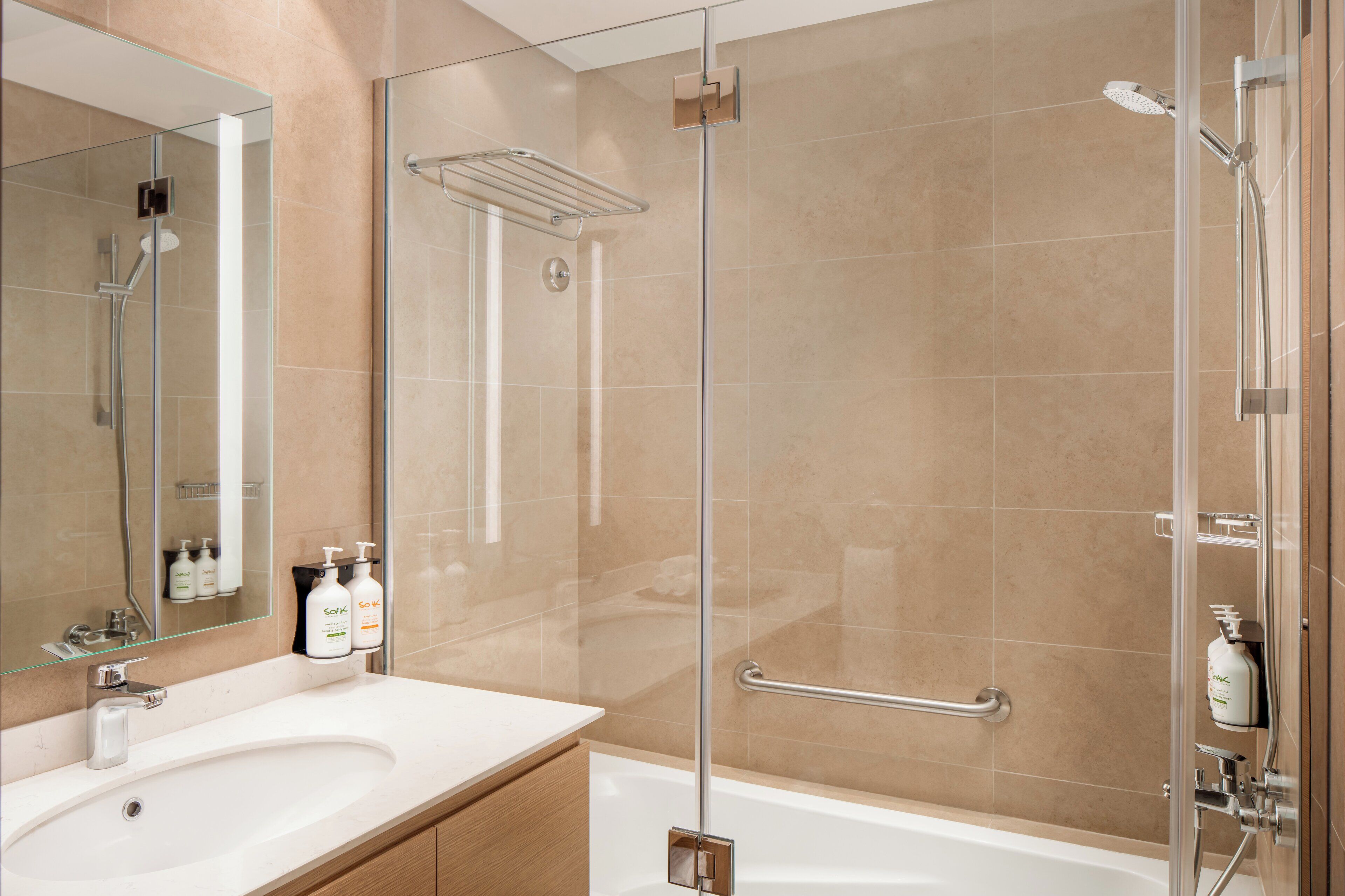 Un baño moderno con cabina de ducha de vidrio, lavamanos blanco y espejo.
