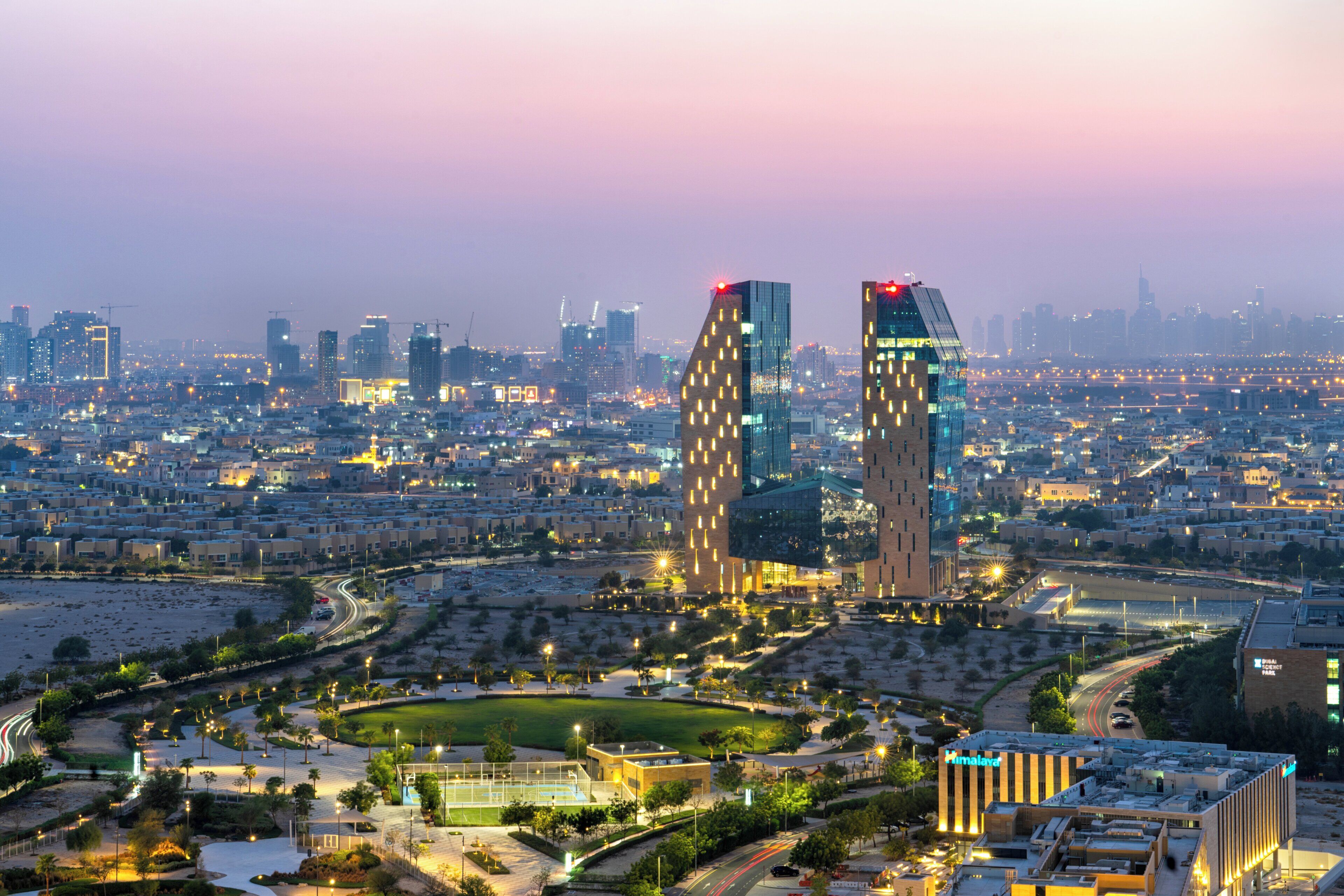A cityscape with modern buildings, a large open park, and a stadium.