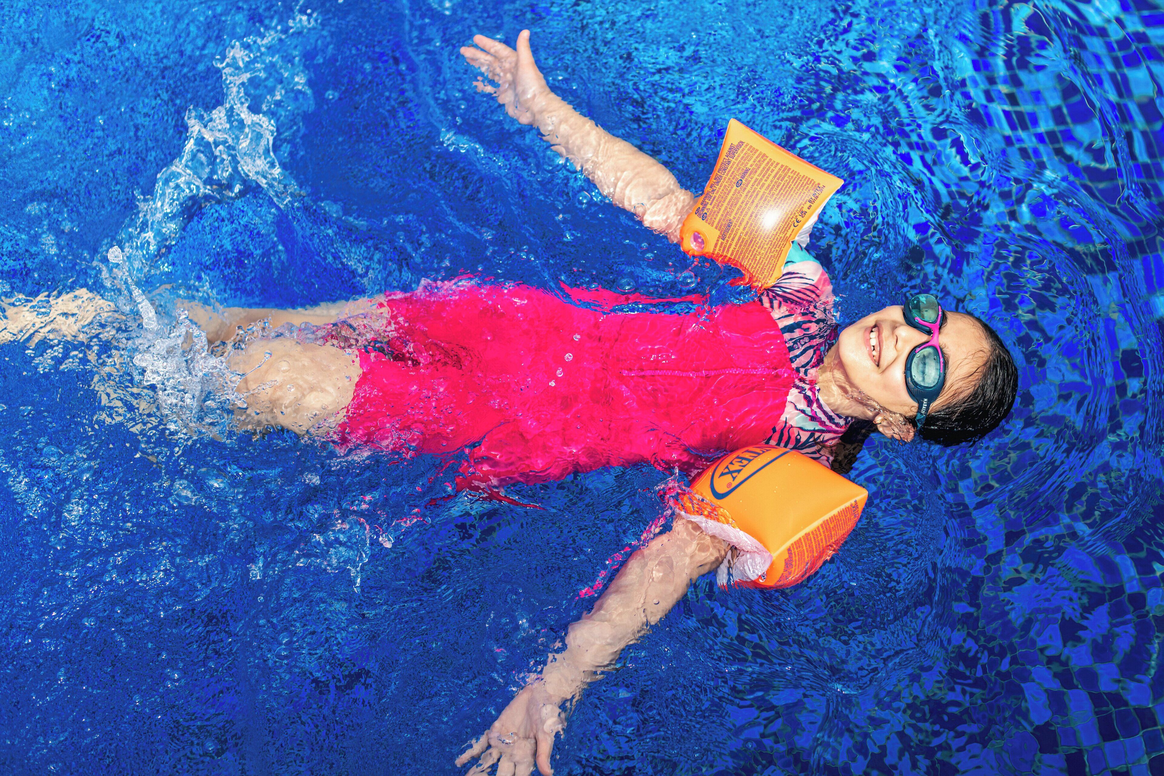 A person floating in a pool with a book and a kickboard.