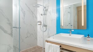 A modern bathroom with a glass shower enclosure, a white sink, and a mirror with a blue accent wall. - Holiday Inn Express Qingdao Northern West Coast by IHG (Qingdao)