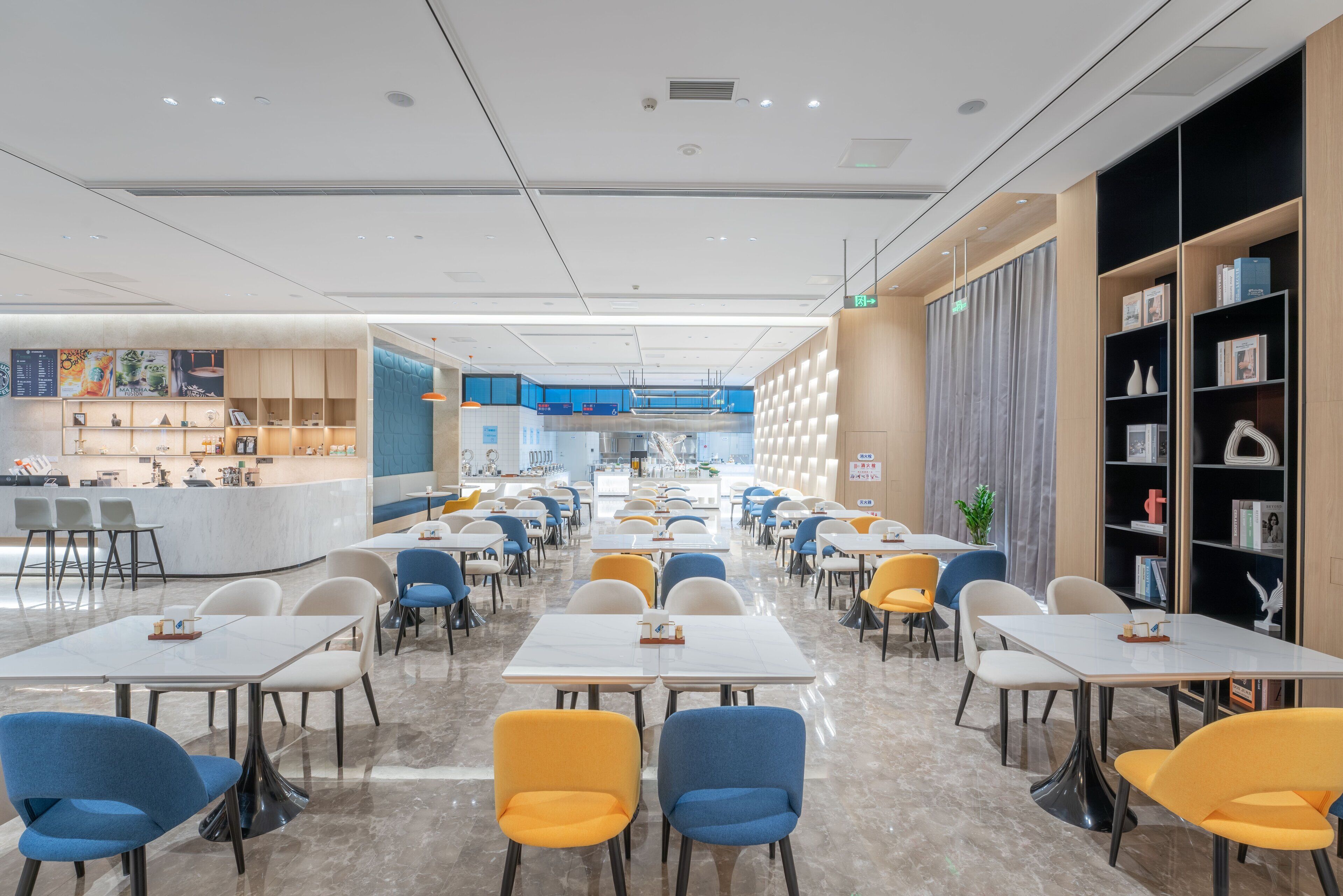 A modern restaurant with a central counter, multiple dining tables, and chairs.