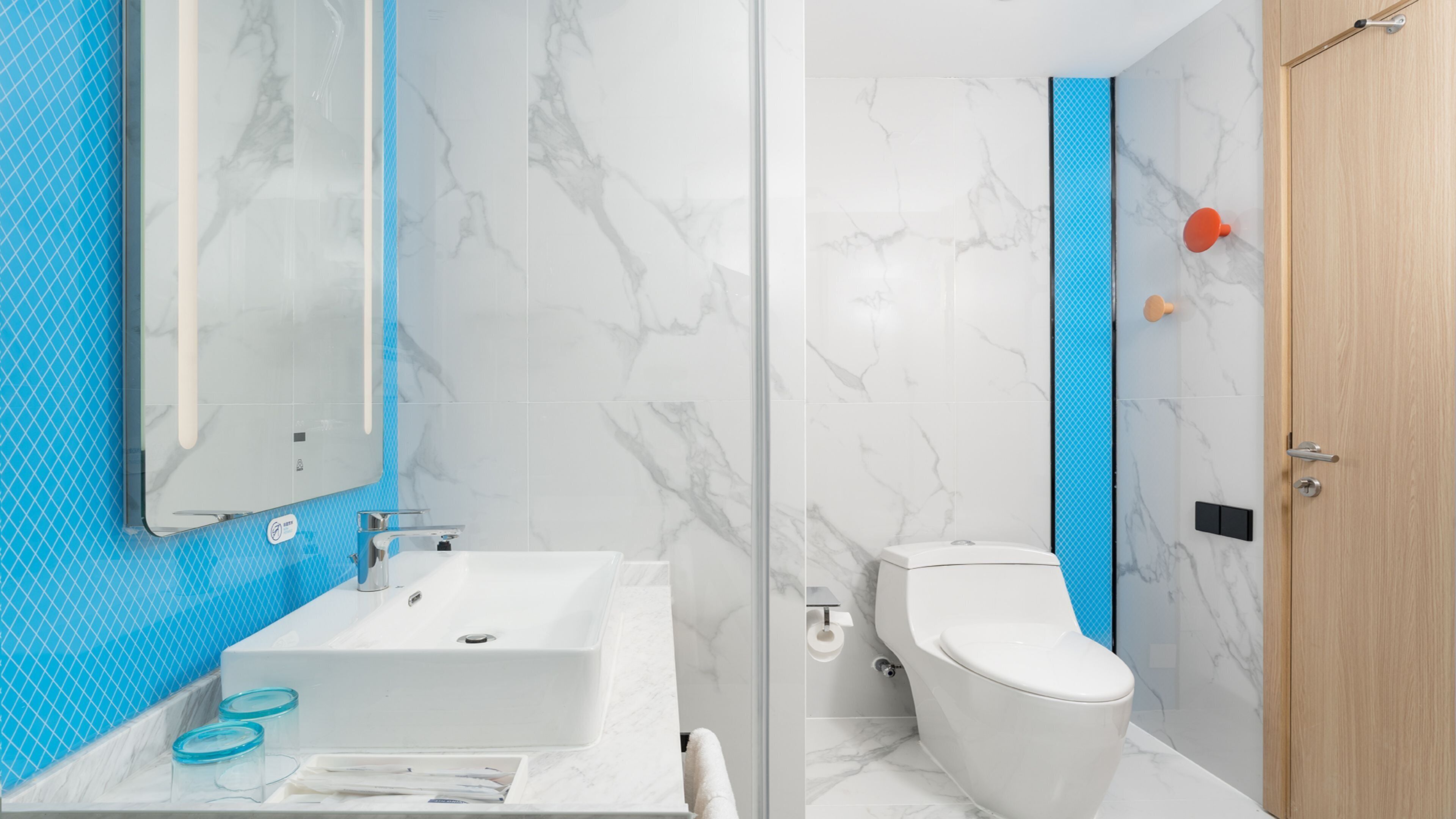 A bathroom with a white sink, a mirror, a toilet, and a shower area.