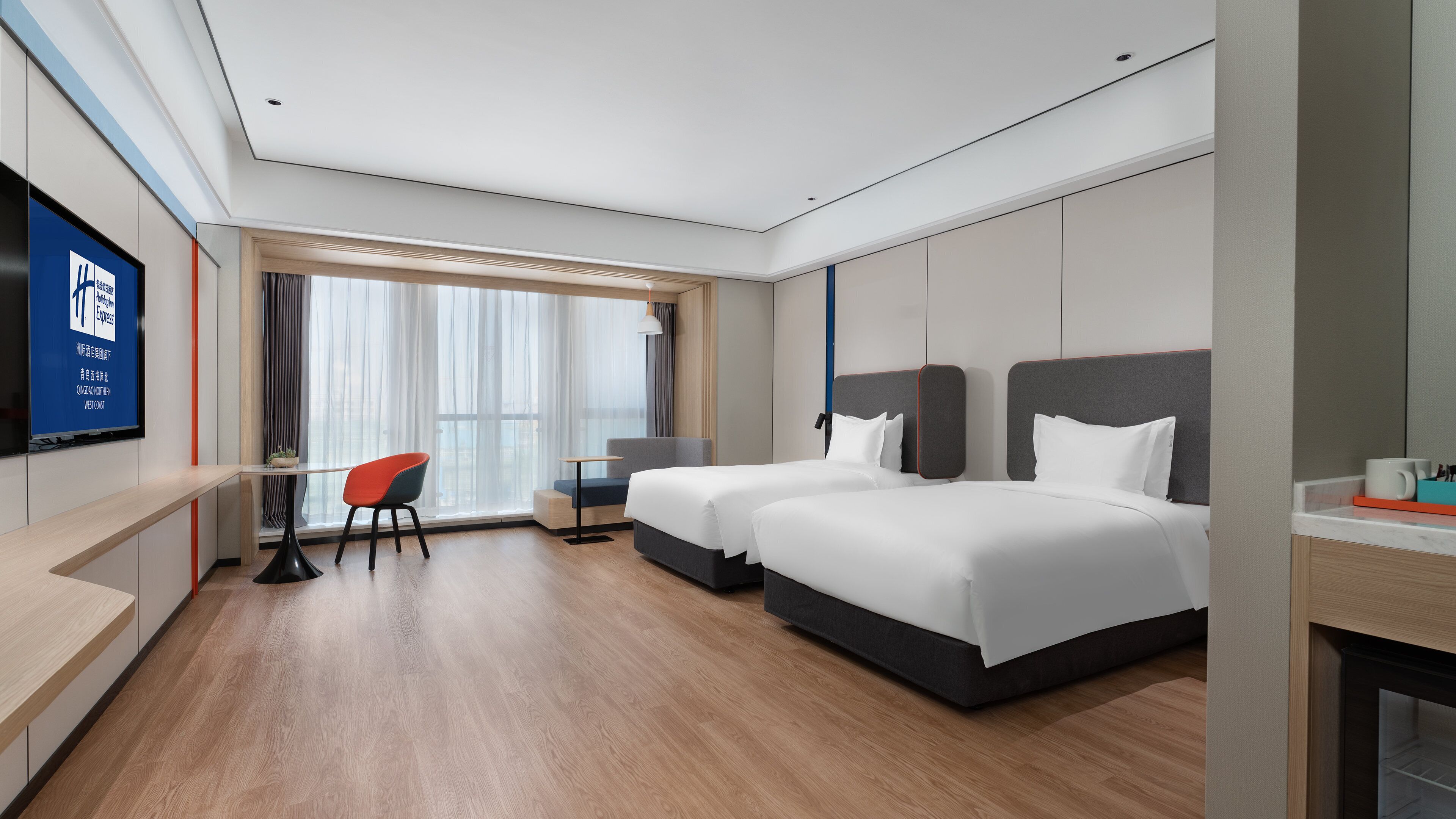 Una habitación de hotel moderna con dos camas, un escritorio, una silla y un televisor en la pared.