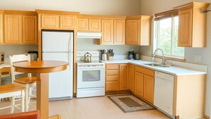 A kitchen with wooden cabinets, a white refrigerator, a stove, a sink, and a window.