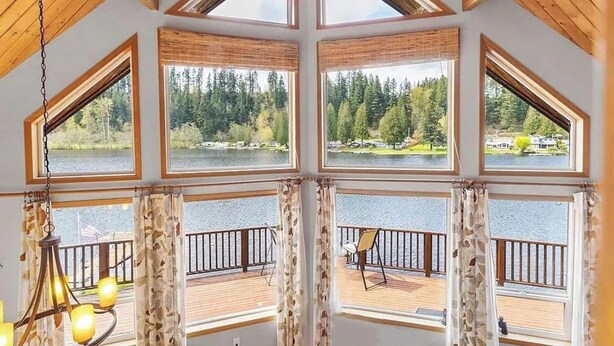 A room with large windows offering views of a lake and forest. - ~Lakefront Property ~ 23 miles to Mt. Rainier! (Eatonville)