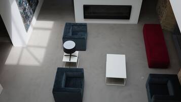 Una sala de estar moderna con un sofá modular, una mesa de centro redonda y un reposapiés rojo.