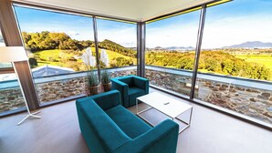 Een moderne woonkamer met een groot raam, een blauwgroene bank en een bijzettafeltje.
