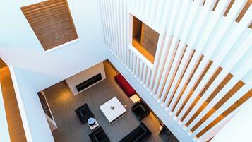 A modern interior with a central seating area, a small kitchen, and a view of the outdoors.