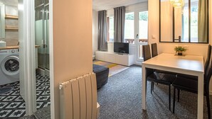 Een modern appartement met een eethoek, een woonkamer met televisie en een wasruimte met een wasmachine.