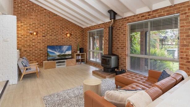 Ein gemütliches Wohnzimmer mit Backsteinwand, Fernseher, Kamin und bequemer Couch.