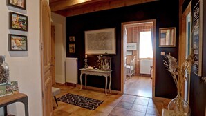 A cozy room with a wooden ceiling, a white radiator, a patterned rug, and a framed map on the wall. - Charming cottage near ski trails, 2 bedrooms (Saint-Régis-du-Coin)