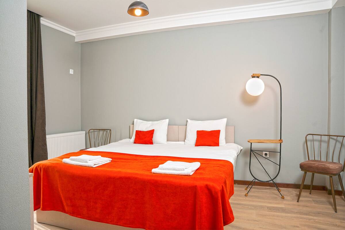 Quarto de hotel com cama, cadeira, luminária de chão e radiador.