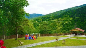 Un parque con un área de juegos, mesas de picnic y una zona cubierta para sentarse.