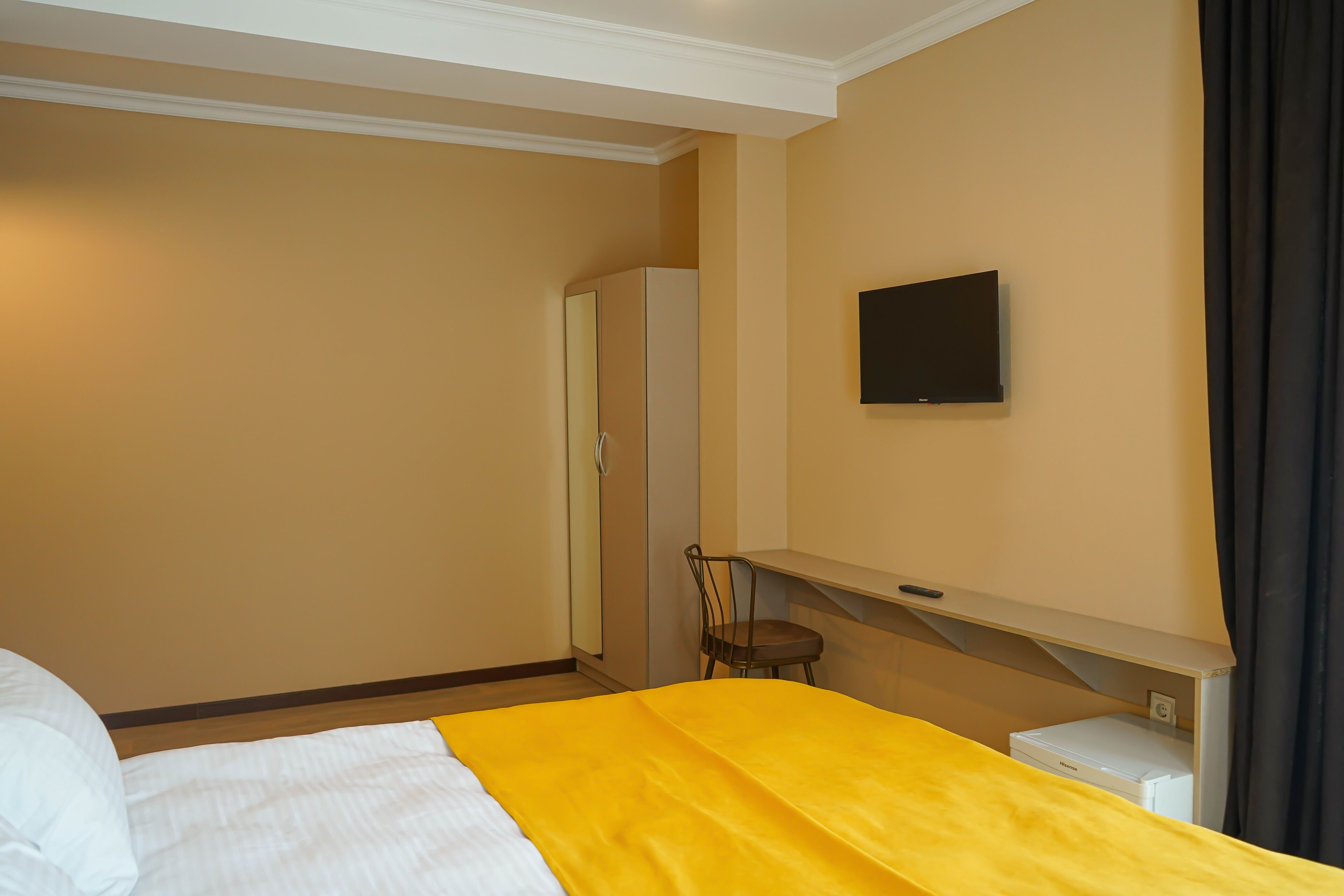 Una habitación de hotel con una cama, una silla, un televisor y un escritorio con una impresora.