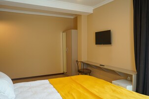 Una habitación de hotel con una cama, una silla, un televisor y un escritorio con una impresora.