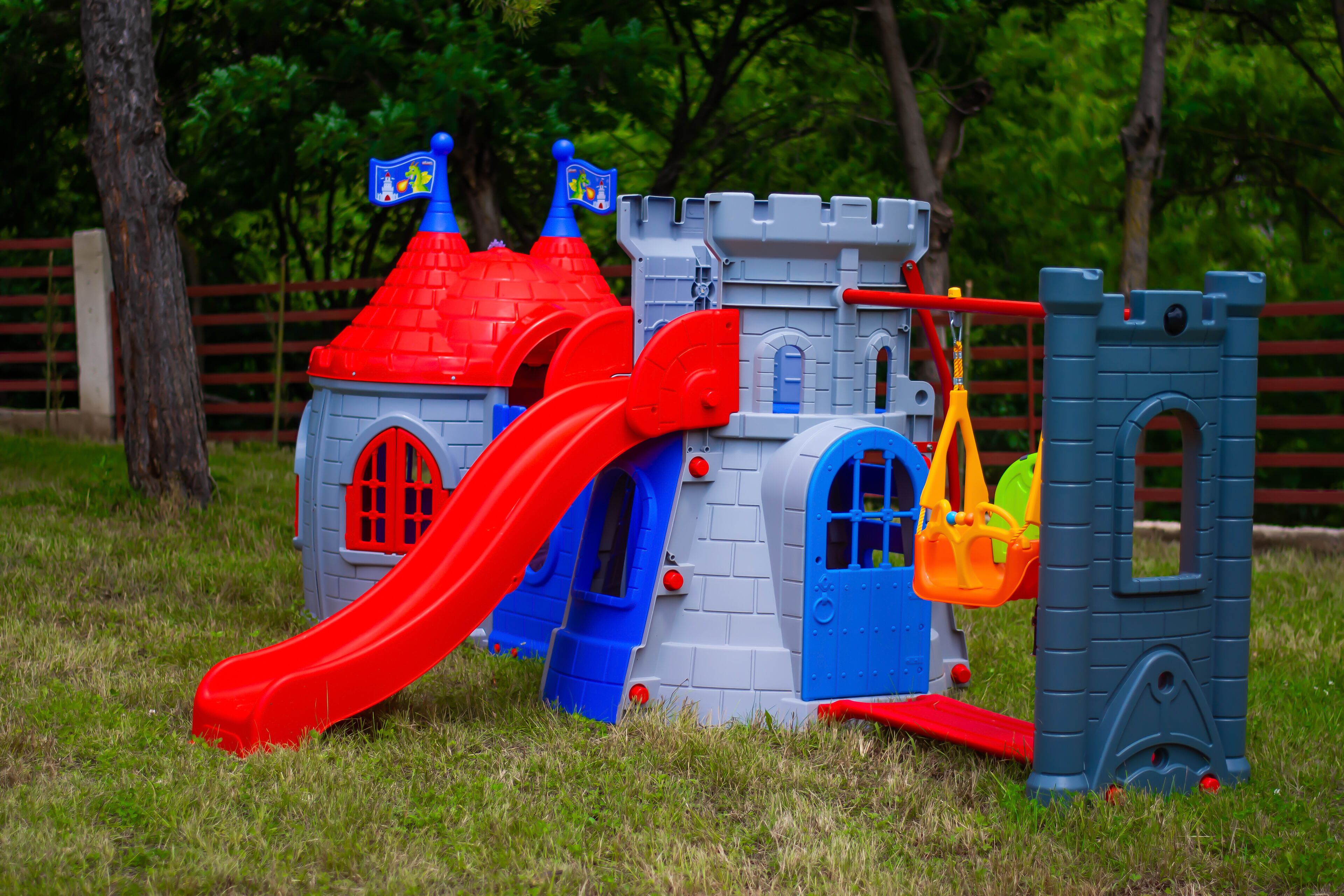 Une structure de jeu en forme de château avec un toboggan rouge et un petit pont.