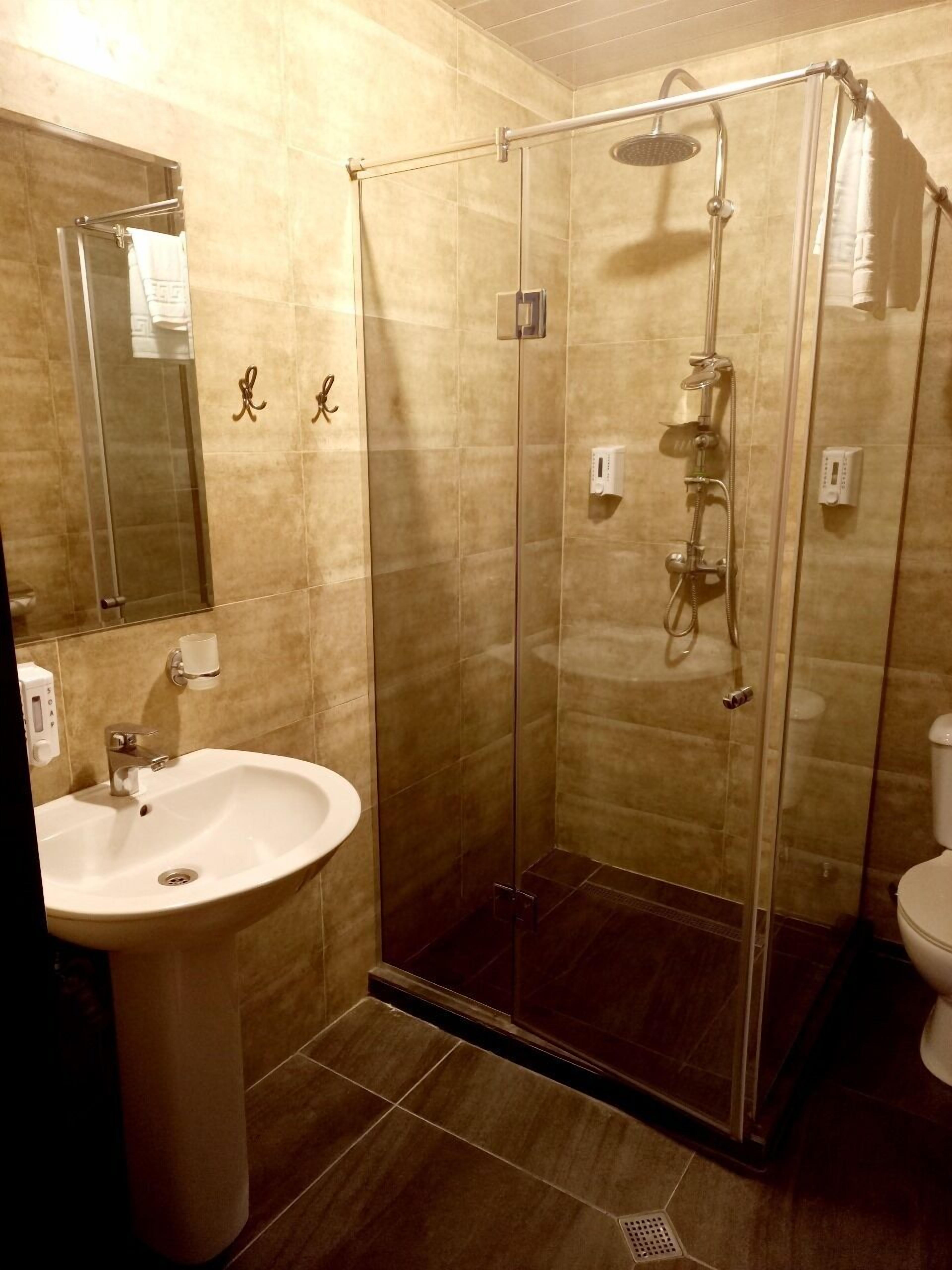 Un baño moderno con ducha de vidrio, lavamanos y retrete.