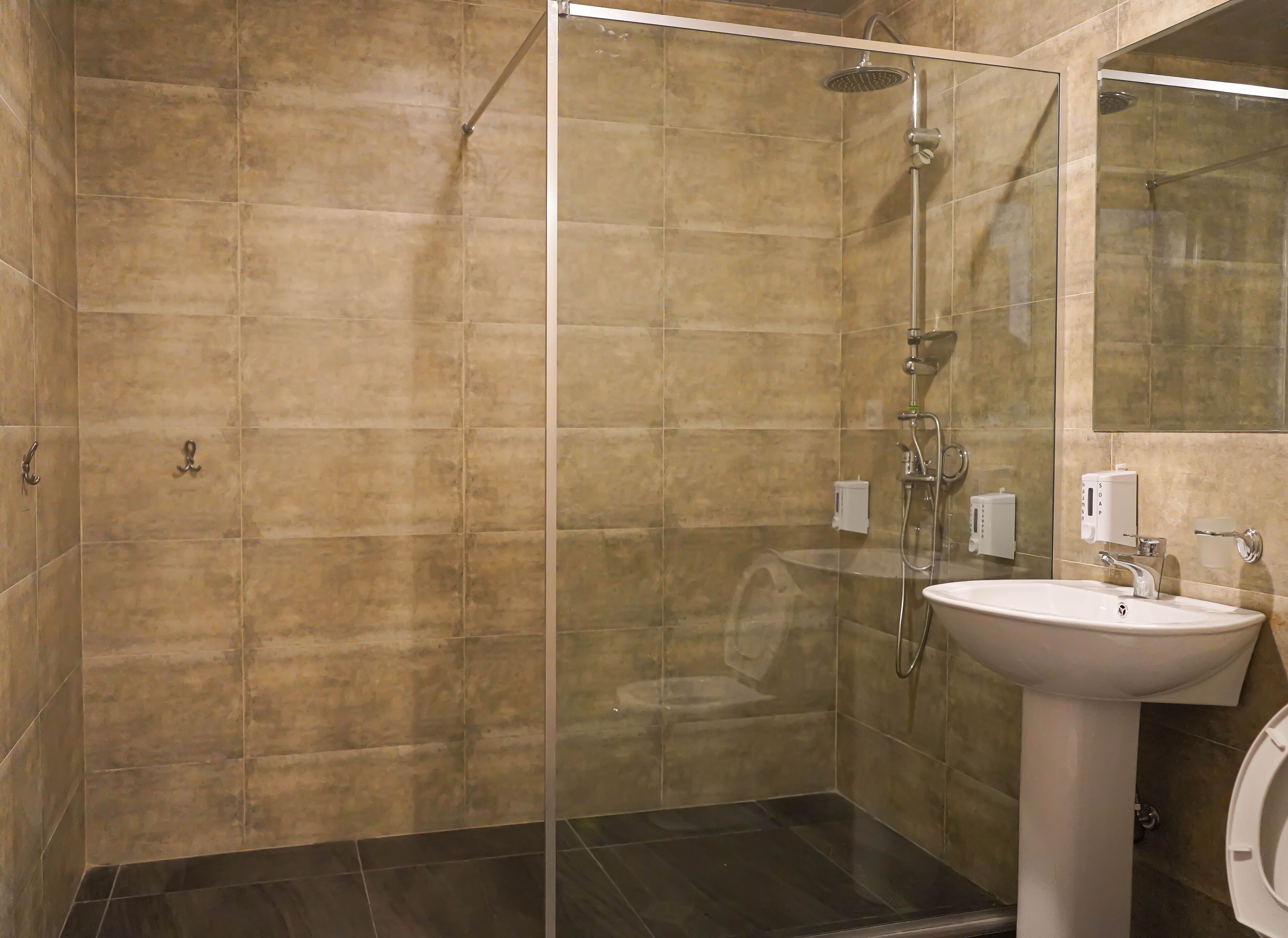 Une salle de bain moderne avec une douche à parois de verre, un lavabo blanc et un grand miroir.