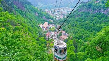 Un teleférico en un valle verde exuberante con un pueblo abajo.