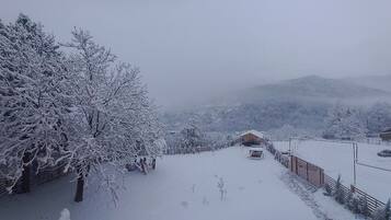 A snow-covered landscape with a wooden cabin and a fence.