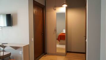 Habitación de hotel compacta con cama, escritorio y televisor.