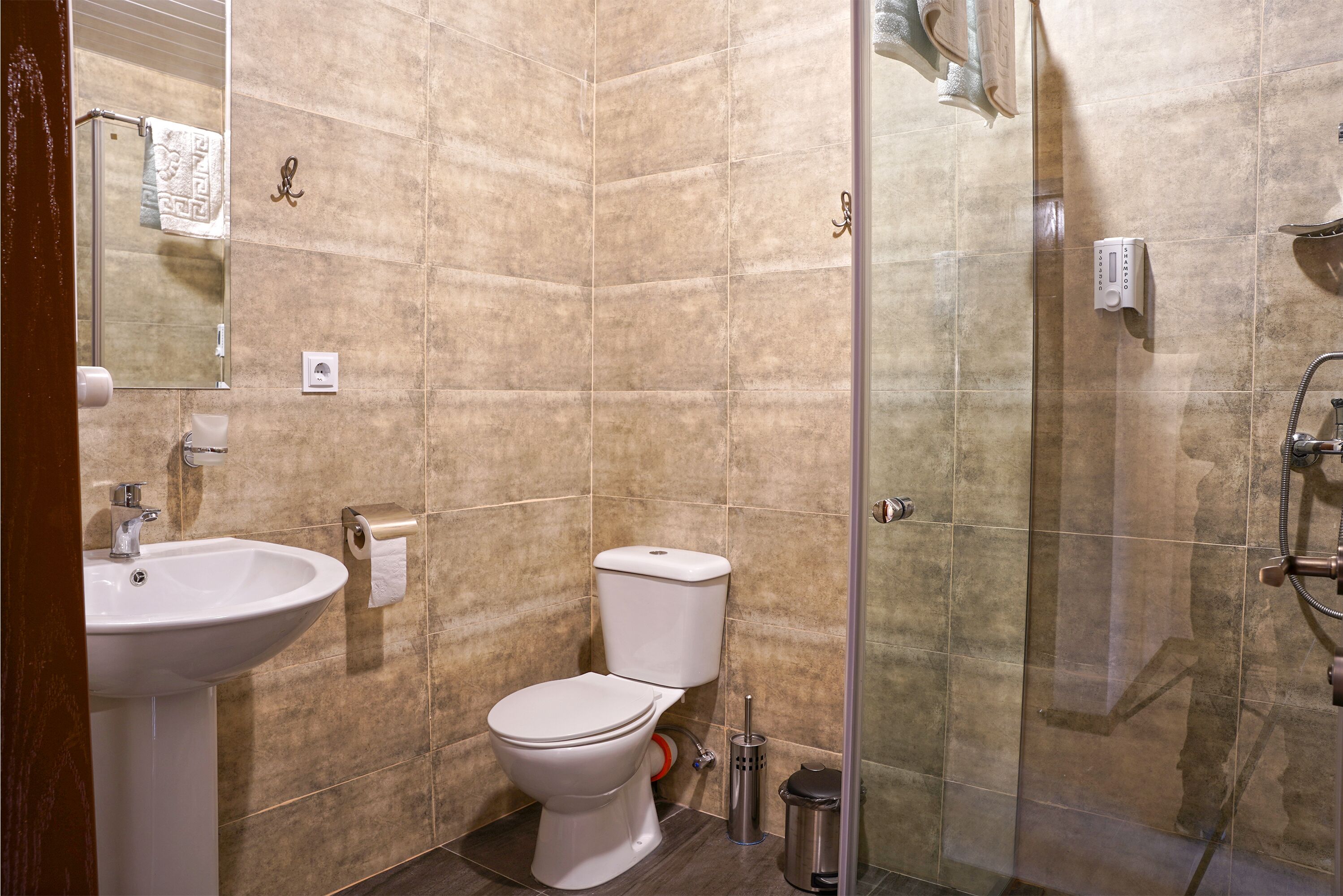 A bathroom with a sink, toilet, and glass shower enclosure.